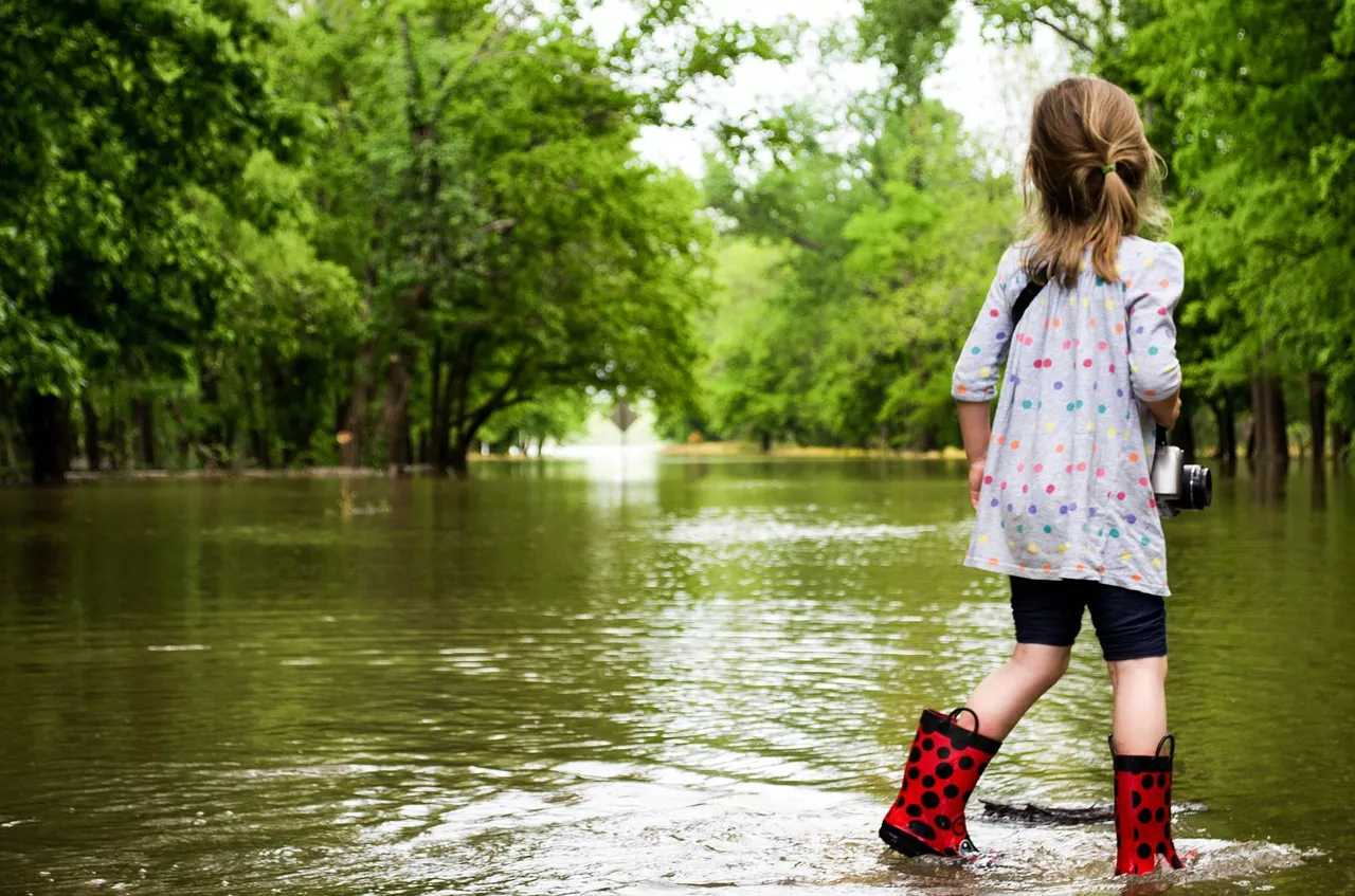 Girl in rain boots on flooded road